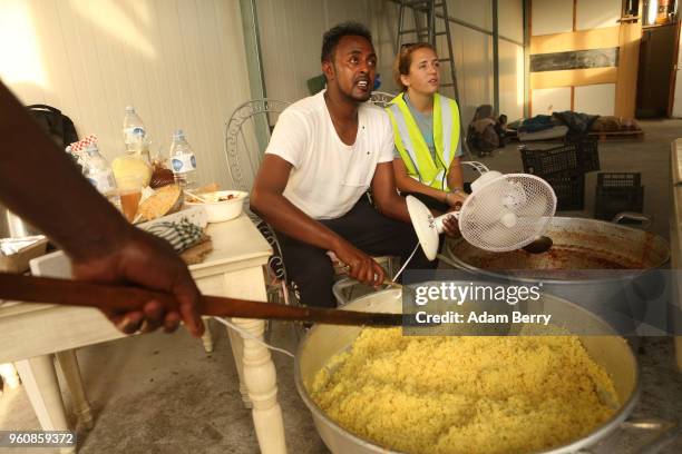 Volunteers and refugees prepare bags of hot beans and rice at an independent, NGO-run food distribution center outside the Moria refugee camp on May...