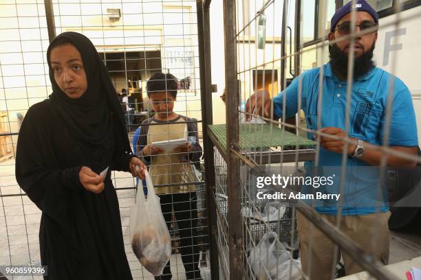 Refugee takes a bag of hot beans and rice at an independent, NGO-run food distribution center outside the Moria refugee camp on May 20, 2018 in...