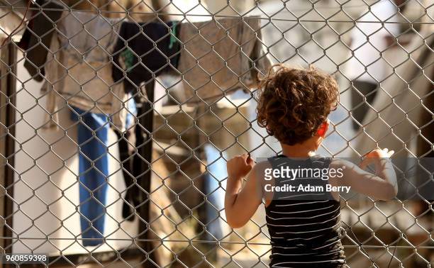 Refugee child looks through a fence at the Moria refugee camp on May 20, 2018 in Mytilene, Greece. Despite being built to hold only 2,500 people, the...