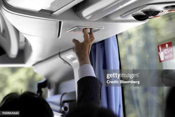 Attendant pushes a button to trigger an automated emergency stop onboard a Hino Motors Ltd. Bus during a demonstration at a test course in Hamura,...