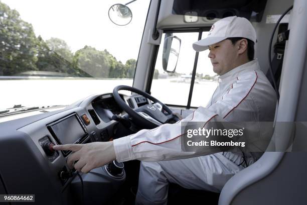 Driver pushes a button to trigger an automated emergency stop onboard a Hino Motors Ltd. Bus during a demonstration at a test course in Hamura, Tokyo...