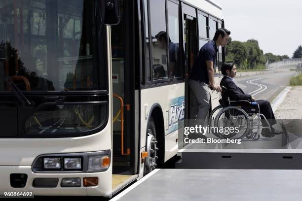 An attendant pushes a wheelchair out of a Hino Motors Ltd. Autonomous bus during a demonstration at a test course in Hamura, Tokyo Metropolis, Japan,...