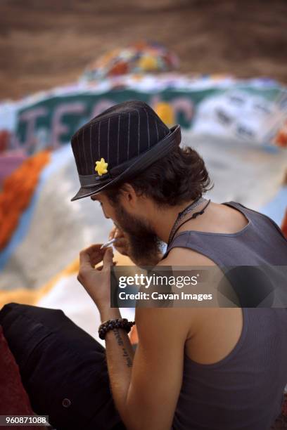 high angle view of man holding weed while sitting at salvation mountain - marijuana tattoo stock pictures, royalty-free photos & images