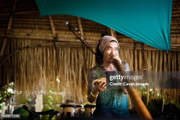 happy musician playing alpenhorn during event - alphorn stock-fotos und bilder