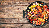 Assorted delicious grilled meat and bratwurst with vegetables on grill