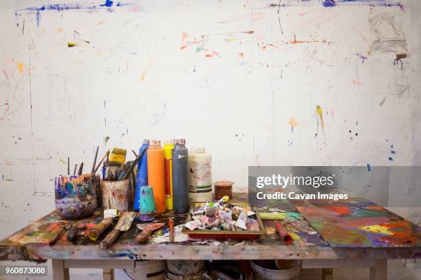 art equipment on messy table against wall - kunstatelier stockfoto's en -beelden