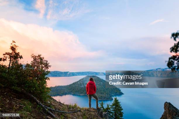 rear view of woman standing on cliff against crater lake - crater lake stock pictures, royalty-free photos & images