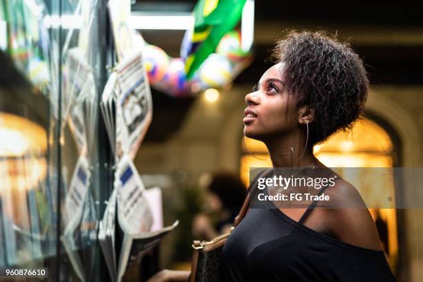 afro young woman looking for the news at newsstand - maceió stock pictures, royalty-free photos & images