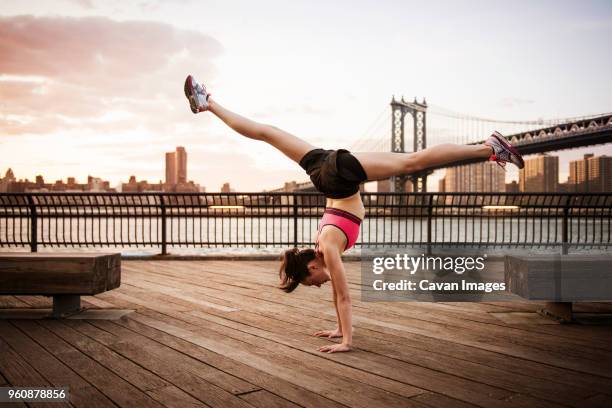 woman doing splits on handstand at promenade against manhattan bridge - handstand stock pictures, royalty-free photos & images