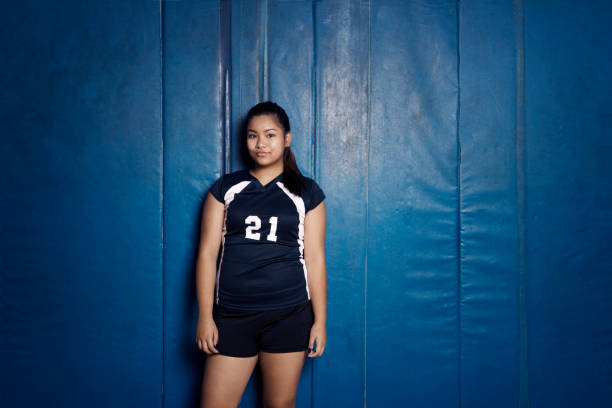 portrait of confident teenage girl standing against blue wall - girls volleyball stock pictures, royalty-free photos & images
