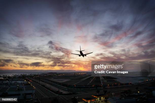 silhouette airplane landing at airport - airplane lights stock pictures, royalty-free photos & images