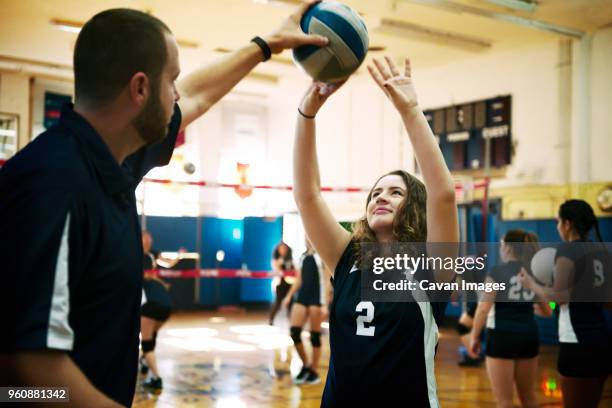 male coach teaching girl in volleyball court - zaalvolleybal stockfoto's en -beelden