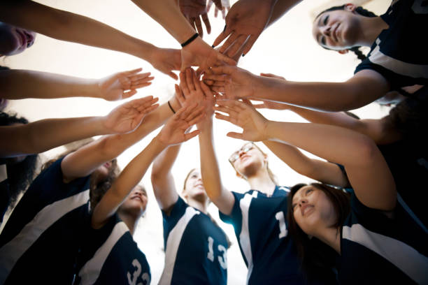 low angle view of female volleyball sports team huddling - girls volleyball stock pictures, royalty-free photos & images