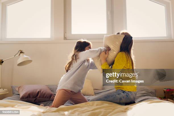 sisters fighting with pillows on bed at home - sibling fight stock pictures, royalty-free photos & images