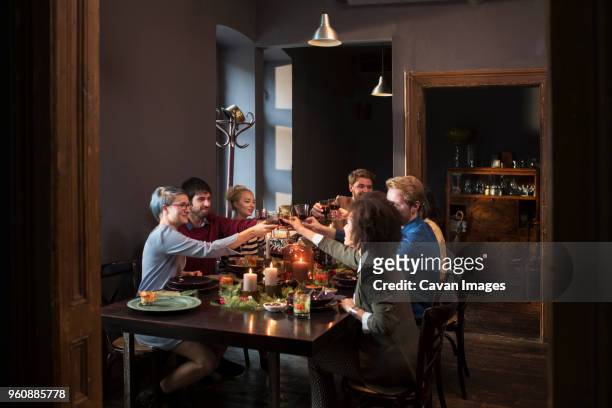 friends toasting wine while having meal at table during christmas - victory dinner stockfoto's en -beelden