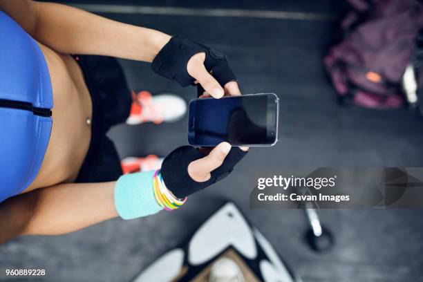 overhead view of female athlete using smart phone at gym - protective sportswear ストックフォトと画像