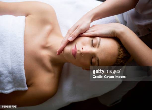 woman receiving massage from female therapist in spa - cavan images stockfoto's en -beelden