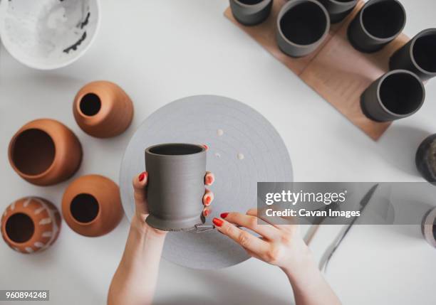 cropped hands of female potter making ceramics at table in workshop - tonkeramik stock-fotos und bilder