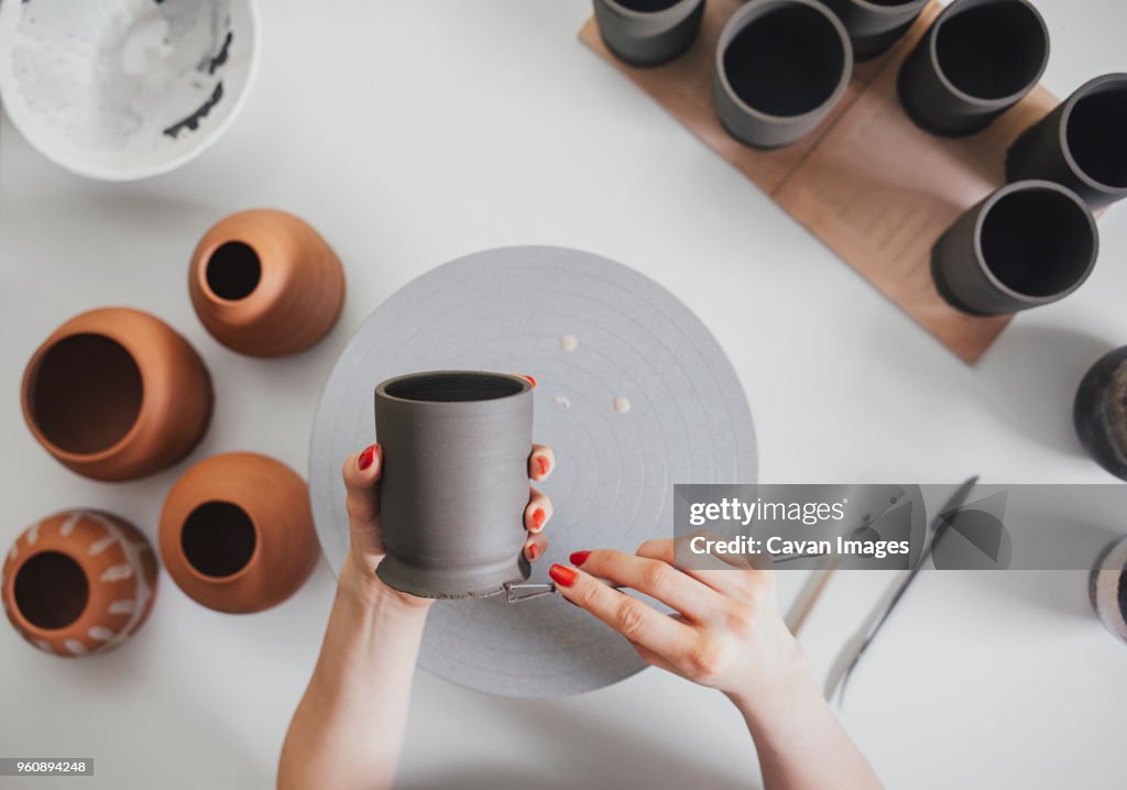 Cropped hands of female potter making ceramics at table in workshop