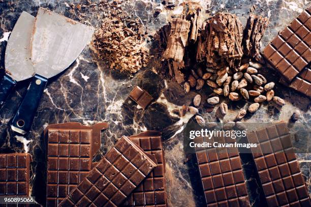 overhead view of chocolate bars with nuts and kitchen knife on table - chocolate chunks top view stock pictures, royalty-free photos & images