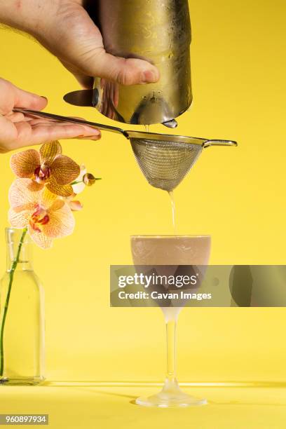 cropped image of hands preparing drink against yellow background - colander foto e immagini stock