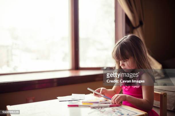 girl holding felt tip pen at table in living room - felt tip pen stock-fotos und bilder