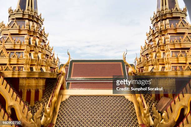 roof of ordination hall is seen bettwen two golden spires of loha prasat - sunphol foto e immagini stock