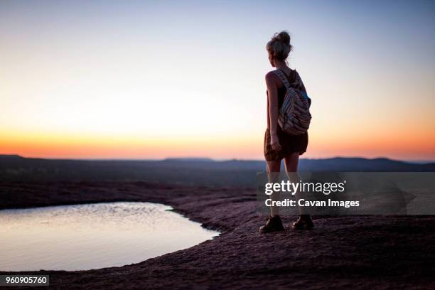 rear view of woman walking by pond on field during sunset - hill country stock pictures, royalty-free photos & images