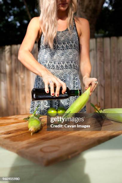 midsection of woman pouring olive oil on corn - corn oil foto e immagini stock