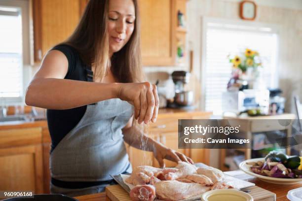 woman seasoning chicken in kitchen - raw chicken stock pictures, royalty-free photos & images