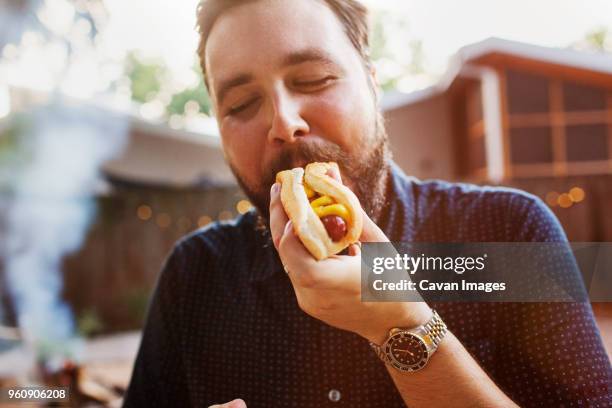 man eating hot dog at yard - hot dog stock pictures, royalty-free photos & images