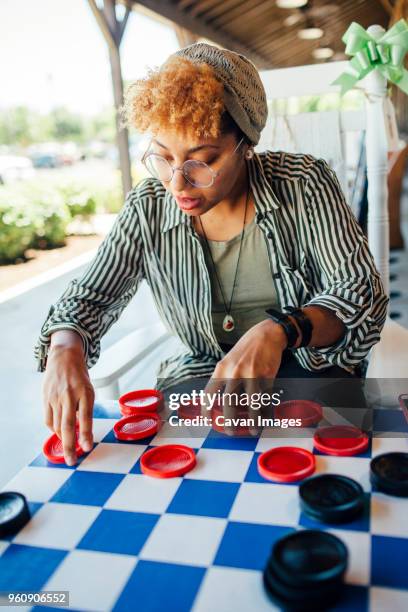 woman playing checkers while sitting at yard - checkers game ストックフォトと画像