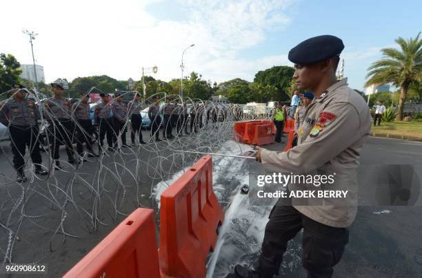 An Indonesian policeman adjusts barbed wires outside the presidential palace during a rally to mark the 20th years of reformation in Jakarta on May...