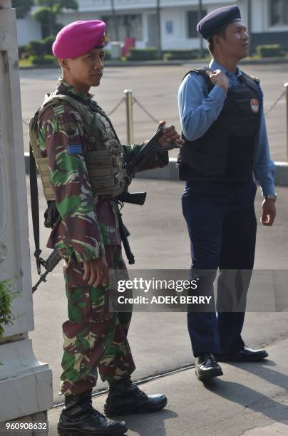 Indonesian soldiers stand guard at the Defence Ministry office while activists march towards presidential palace in a rally to mark the 20th years of...