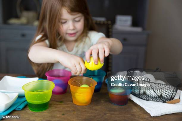 girl coloring easter eggs on table at home - dip dye stock pictures, royalty-free photos & images