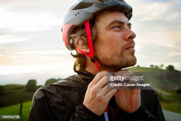 thoughtful man wearing helmet against sky - cycling helmet stock pictures, royalty-free photos & images