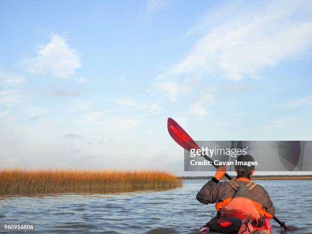 rear view of man kayaking on lake at cape hatteras national seashore against sky - outer banks stock pictures, royalty-free photos & images