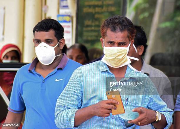 Indian residents wear face mask outside the Medical College hospital in Kozhikode on May 21, 2018. - A deadly virus carried mainly by fruit bats has...