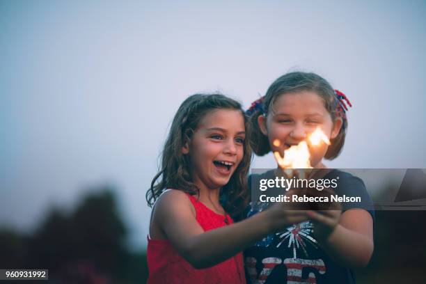 girls holding sparklers smiling - fireworks dusk stock pictures, royalty-free photos & images