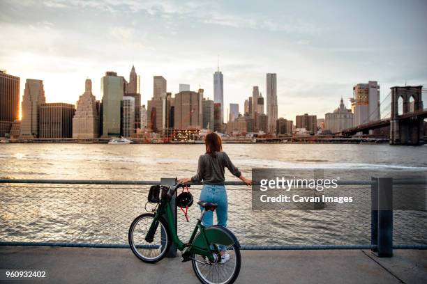 rear view of woman with bicycle looking at city view while standing on observation point - kombinerad mobilitet bildbanksfoton och bilder