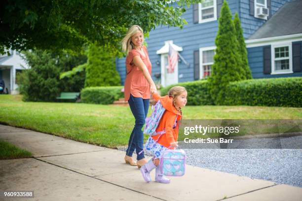 mid adult woman walking with eager daughter on suburban sidewalk - top priority stock pictures, royalty-free photos & images
