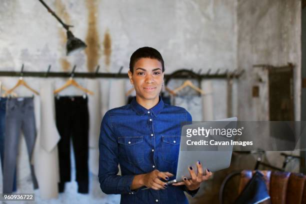 portrait of confident fashion designer holding laptop at workshop - woman tailor stock pictures, royalty-free photos & images