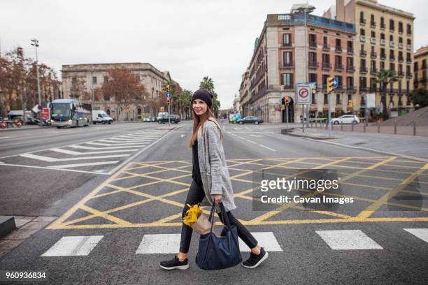 portrait of woman carrying bouquet in bag while walking on city street - carrying bags stock pictures, royalty-free photos & images