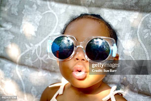 baby girl sitting on lounge chair wearing sunglasses, portrait - baby in sunglass stockfoto's en -beelden