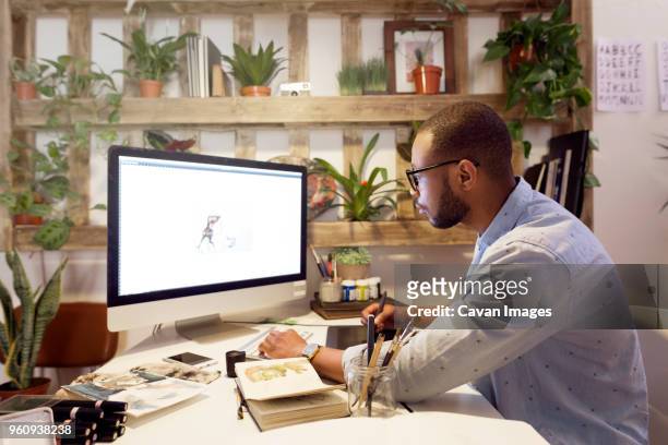 side view of male illustrator making painting on computer in creative office - graphic designer stock-fotos und bilder