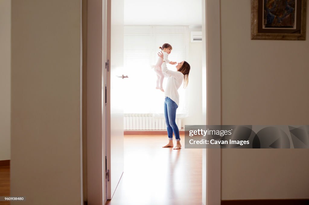 Side view of mother picking girl wearing tutu at home