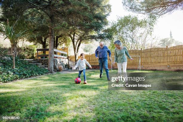 grandparents playing soccer with grandson at yard - senior kicking stock pictures, royalty-free photos & images