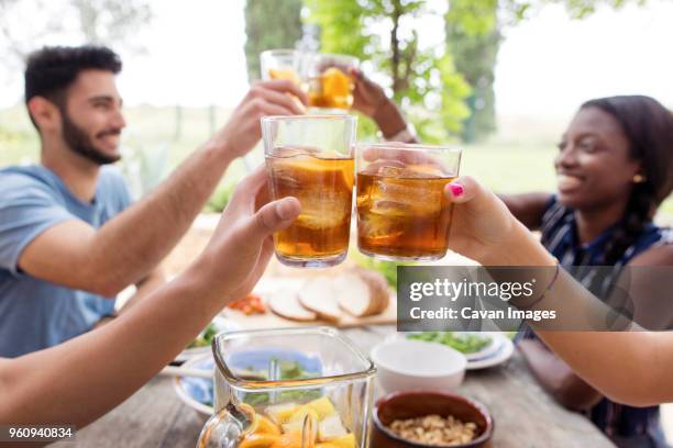 friends toasting iced tea glasses at outdoor table - ice tea stock-fotos und bilder