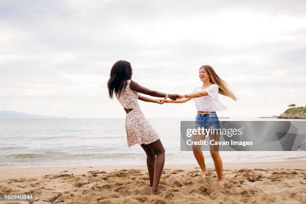 cheerful female friends playing ring-around-the-rosy on beach - ring around the rosy stock pictures, royalty-free photos & images