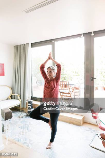 mature woman practicing yoga in tree pose at home - on one leg stock pictures, royalty-free photos & images